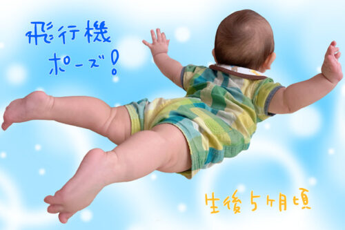 生後５ヶ月頃の赤ちゃんが手足を広げて飛行機のようなポーズをしている写真です。
