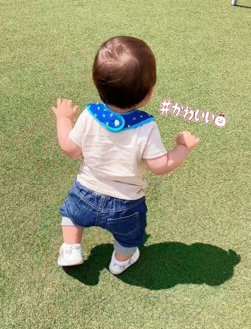 一歳一ヶ月頃の息子のりん太の写真。公園の芝生の上をファーストシューズを履いてバンザイ姿で歩いています。